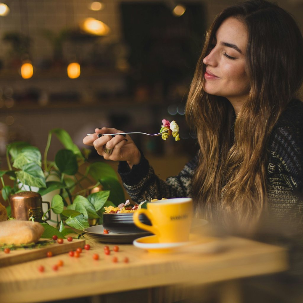 Guest enjoying food and coffee at a plant-filled café table with trailing greenery