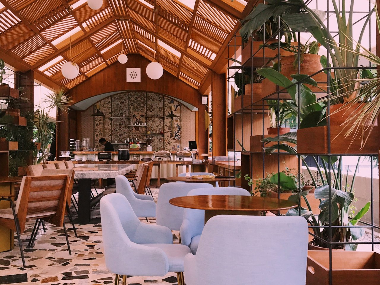 Light-filled café and bar room full of hanging houseplants, set with tables ready for a Plant Night Out event
